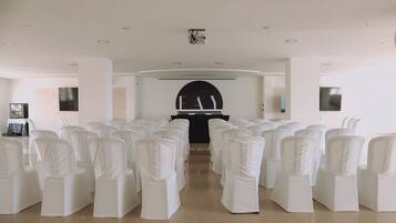 A conference room with rows of white chairs and a podium at the front.
