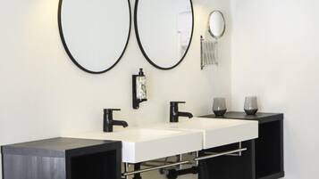 Un baño moderno con lavamanos doble, accesorios negros e iluminación empotrada.