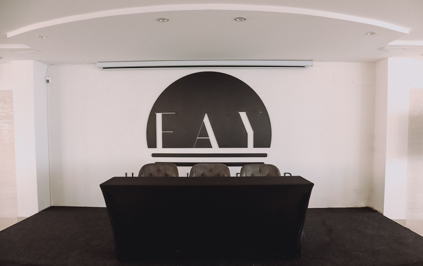 Une salle de conférence équipée d’une table et de chaises, d’un grand panneau fixé au mur et d’un plafond doté d’un éclairage encastré.
