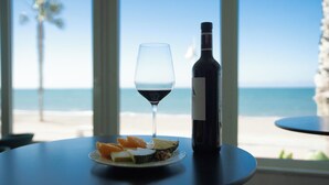A table with a bottle of wine, a glass of red wine, and a plate of fruit by a window with a view of the beach. - Fay Victoria Beach (Rincon de la Victoria)