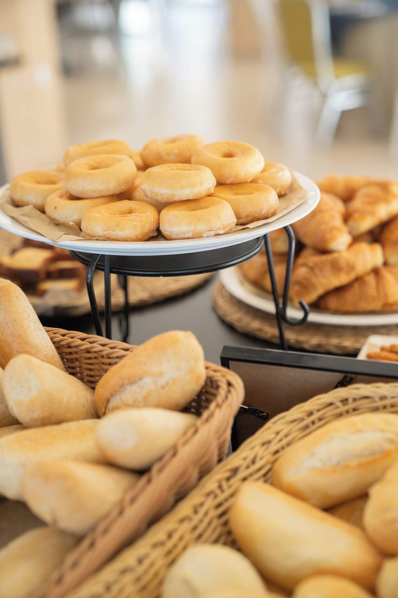 A buffet table with various baked goods including donuts, croissants, and baguettes.