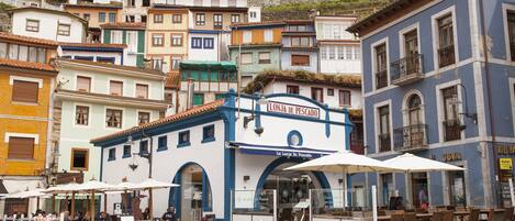 Un edificio costero con fachada azul y blanca, mesas al aire libre y un letrero que dice "La Lonja de Pesca".