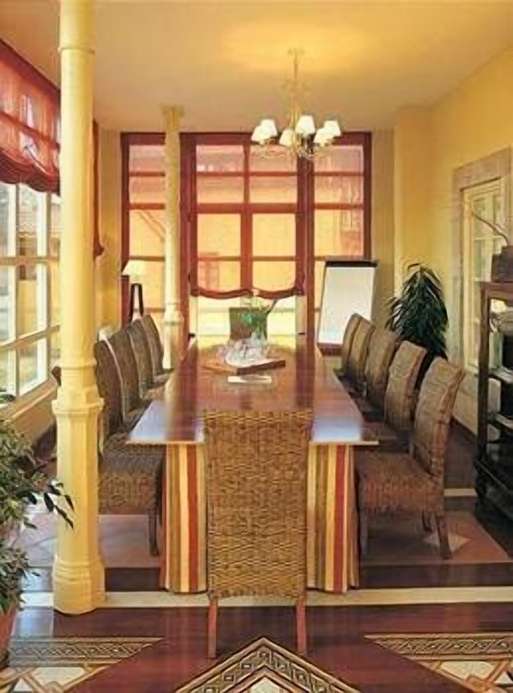 Een eetruimte met een lange tafel, comfortabele stoelen en een kroonluchter.