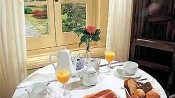 A breakfast table set with a plate of food, a pitcher, a cup, a glass of orange juice, and a basket of bread.