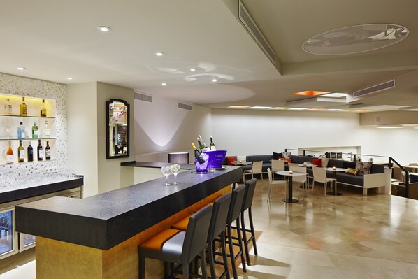 A modern bar area with a counter, bar stools, and a seating area with tables and chairs. - Hotel Palladium (Palma de Mallorca)