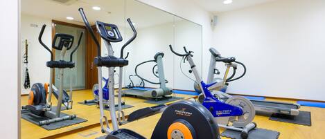 A gym with various exercise equipment, including treadmills and stationary bikes, arranged on mats.