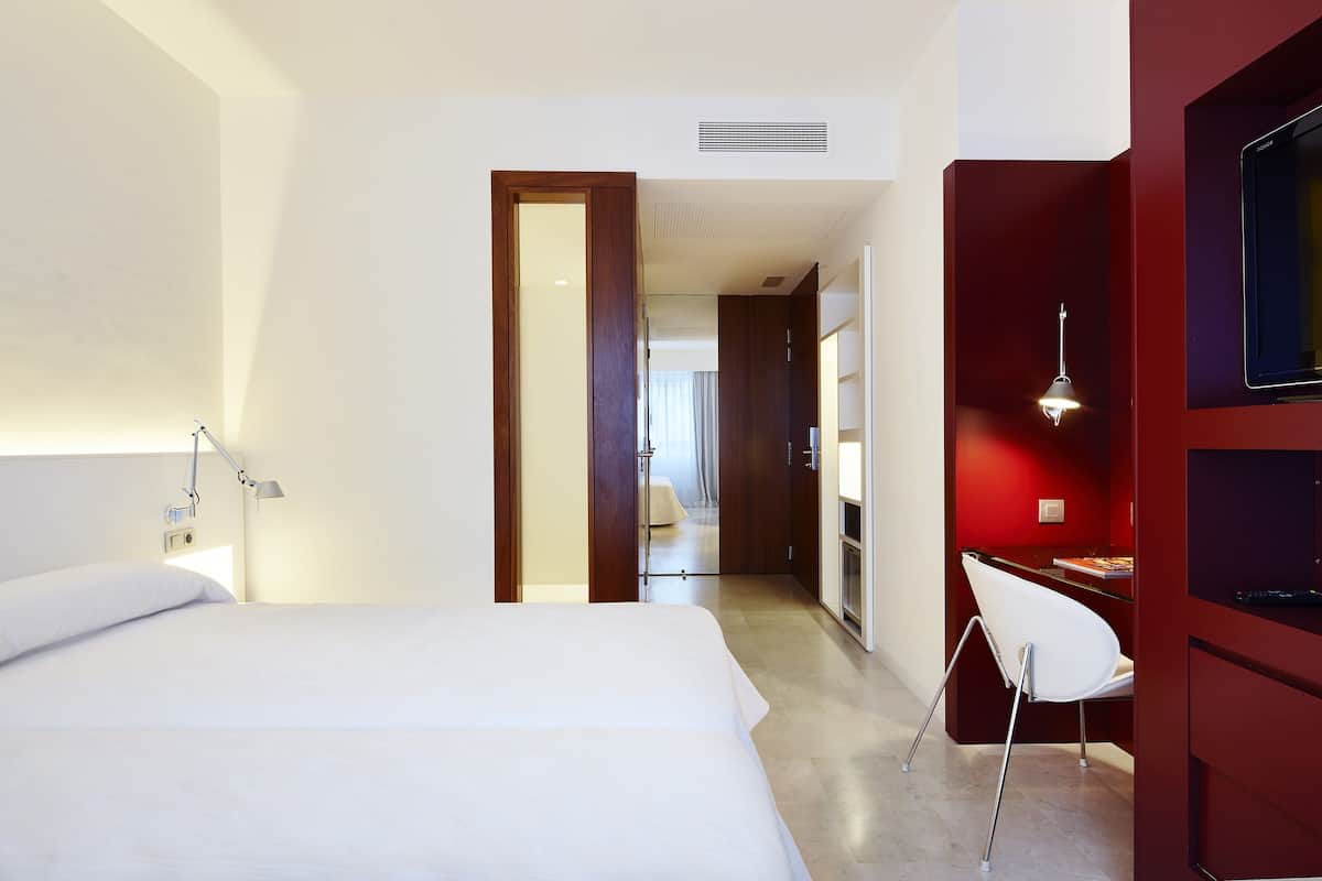 A hotel room with a bed, a desk, and a TV.