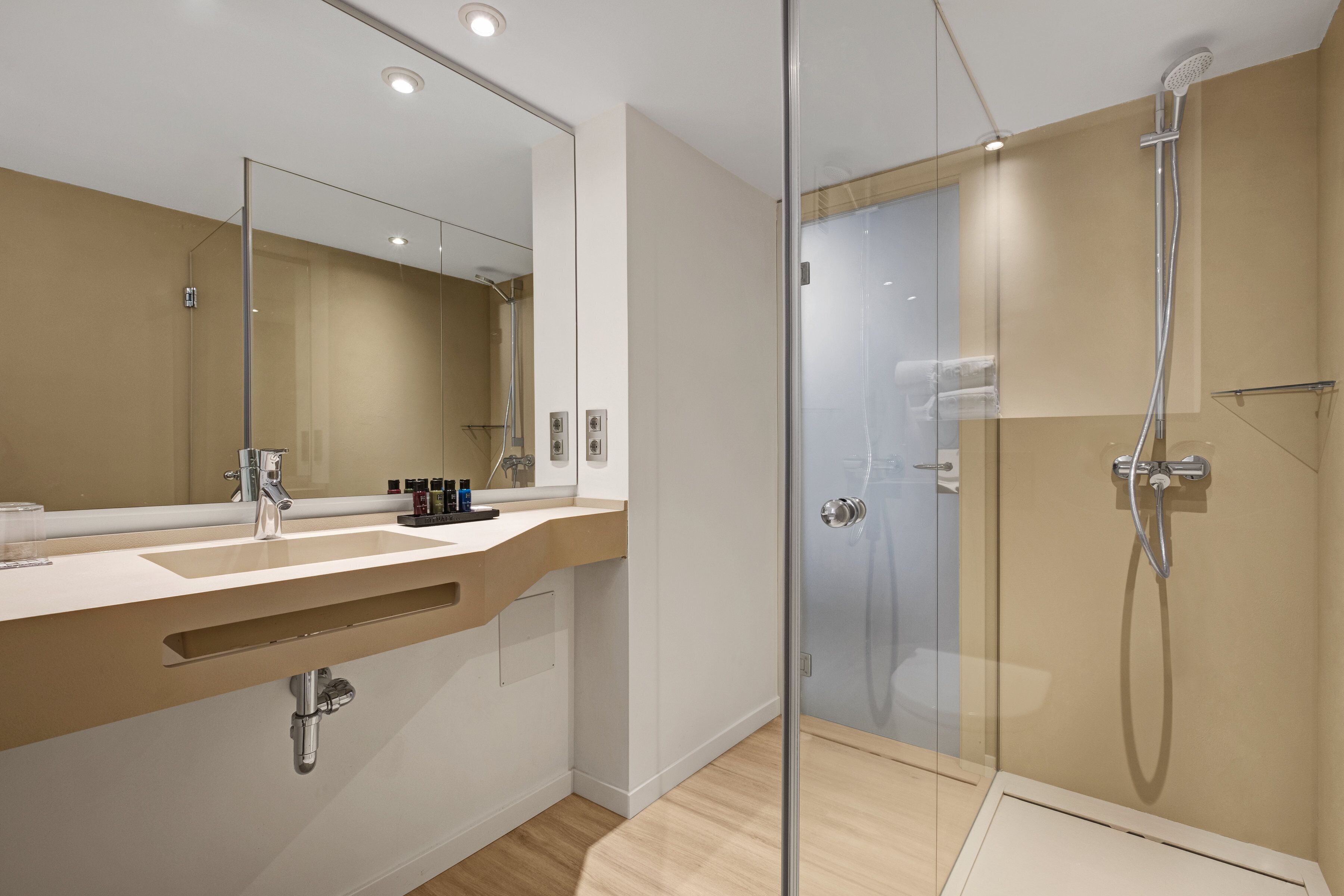 Une salle de bain moderne avec une douche à parois de verre, un grand miroir et un meuble-lavabo en bois.