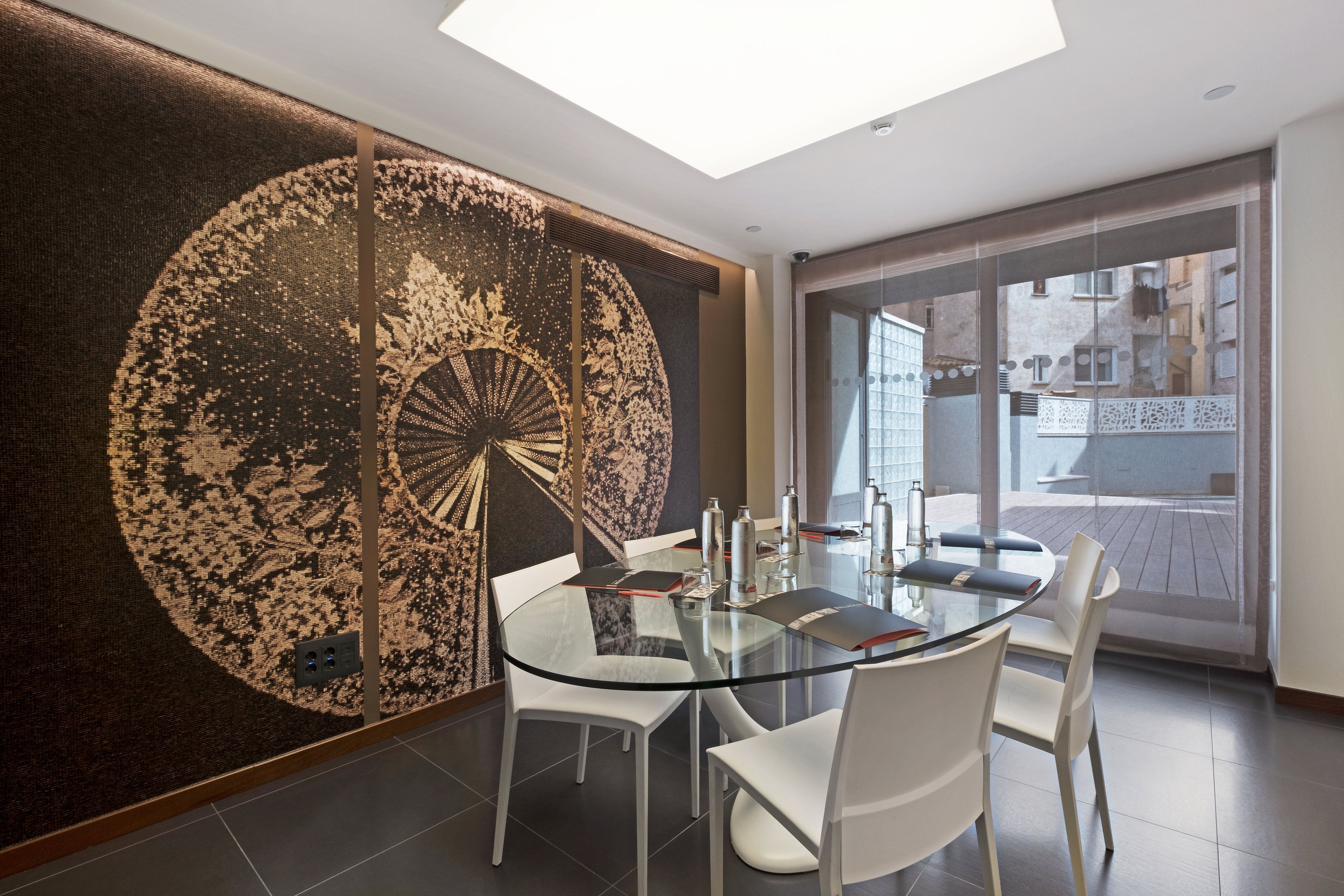 Une salle de conférence moderne avec une table en verre, des chaises blanches et une grande œuvre d’art abstraite qui orne le mur.