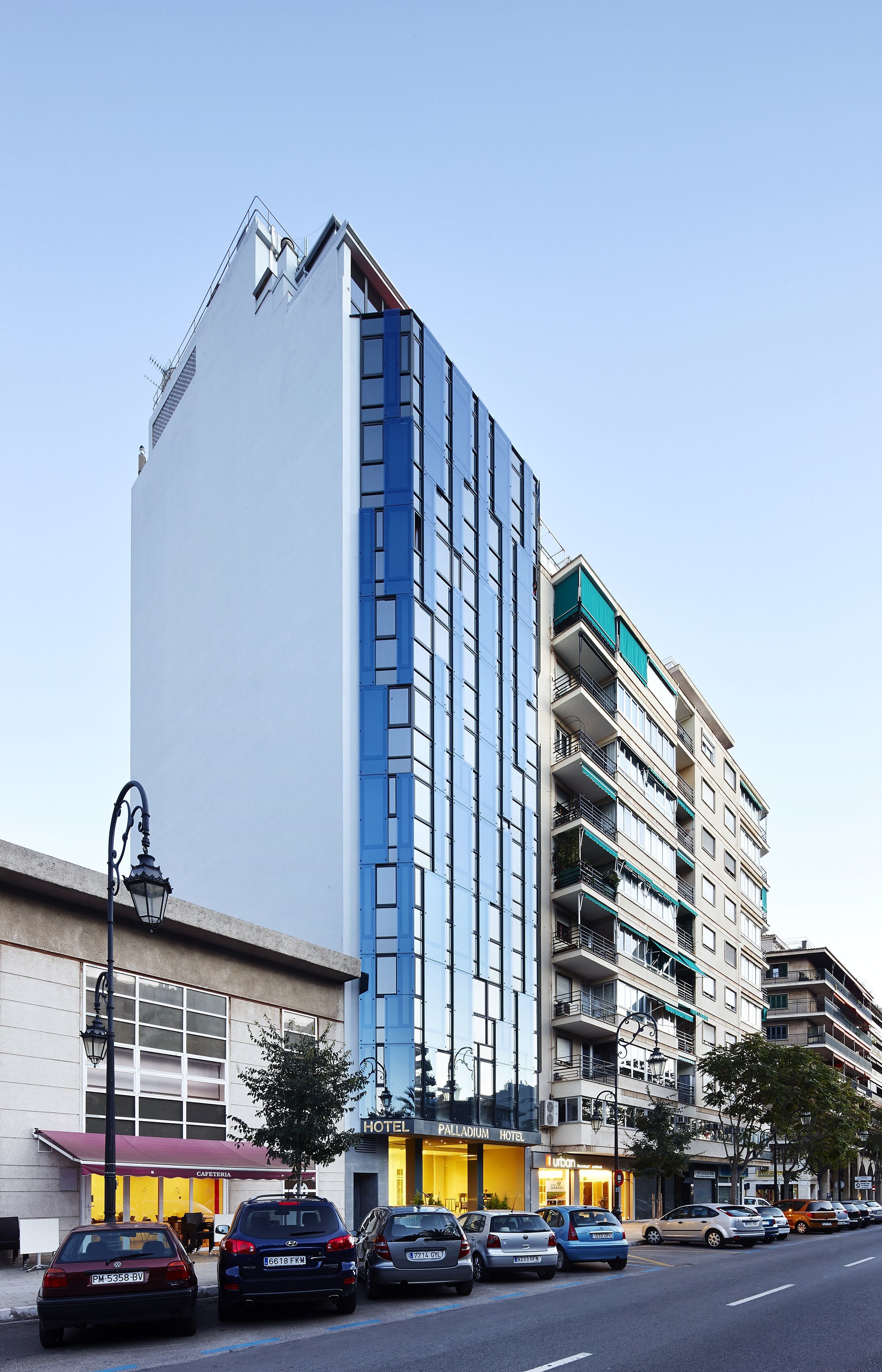 Un hotel de varios pisos con fachada moderna, balcones y entrada visible.