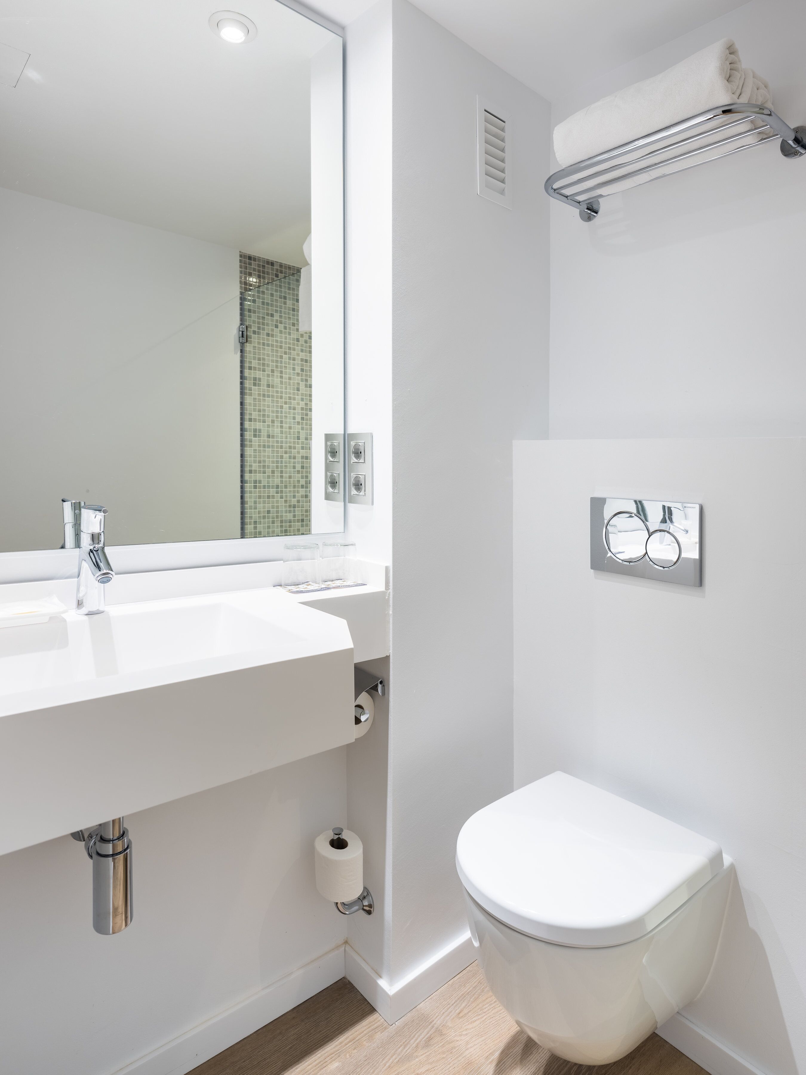 A modern bathroom with a white sink, a toilet, and a mirror.