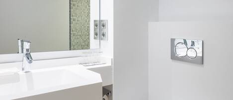 A modern bathroom with a white sink, a toilet, and a mirror.