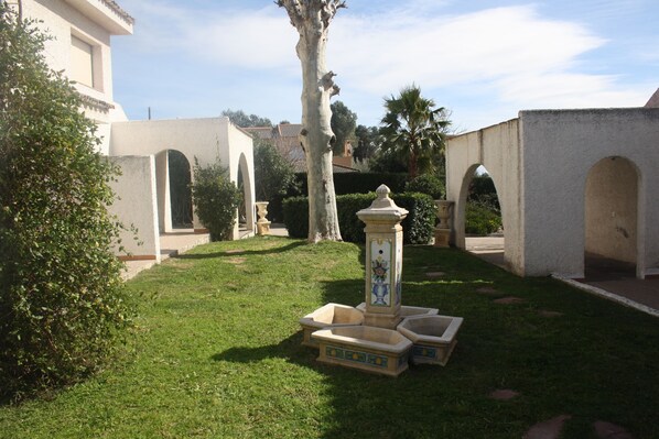 A courtyard with a fountain, palm trees, and a building with arches.