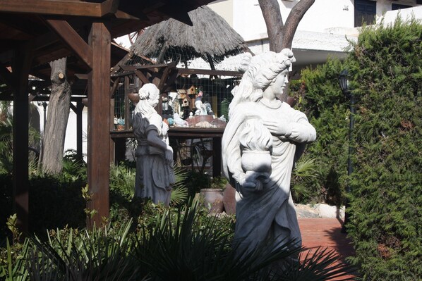 Un jardín con estatuas y un comedero para pájaros.