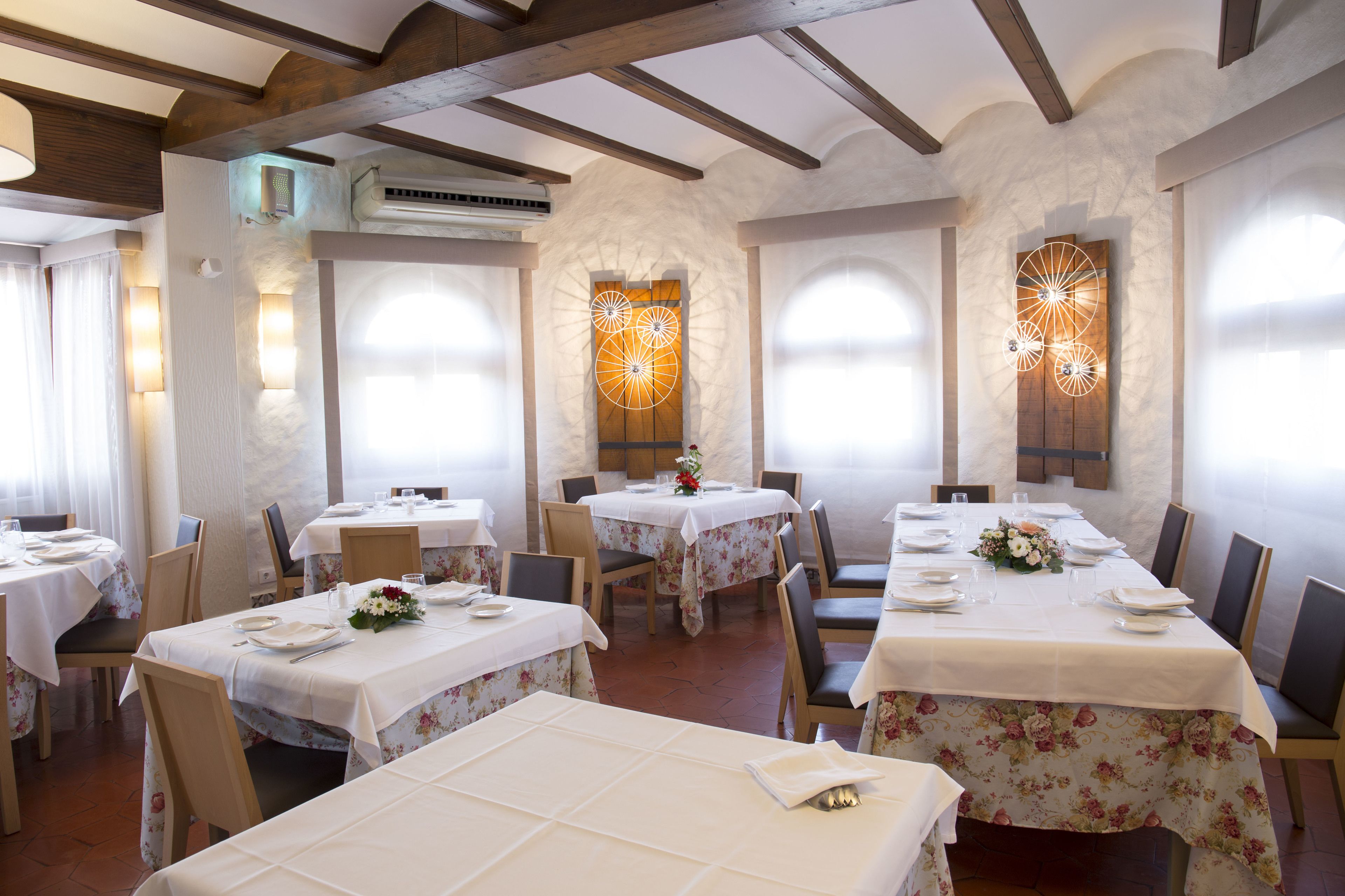 Un restaurante con varias mesas dispuestas para comer, que destaca por su techo de madera rústica y paredes de piedra.