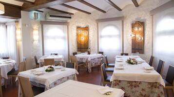 Un restaurante con varias mesas dispuestas para comer, que destaca por su techo de madera rústica y paredes de piedra.