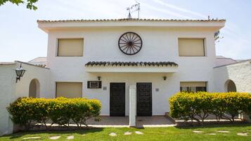 A white building with a tiled roof, two black doors, and a large circular window.