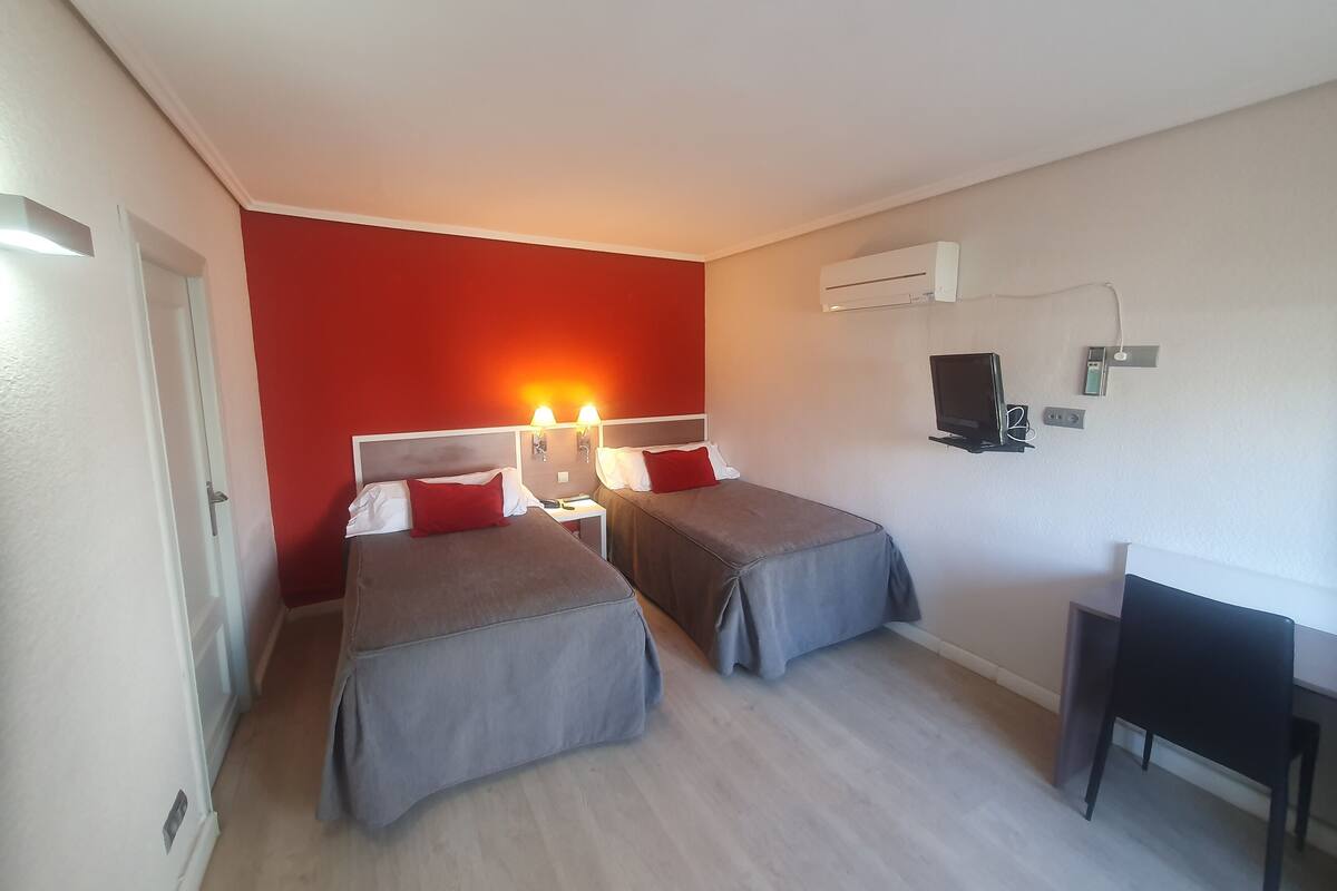 Habitación de hotel con dos camas, un escritorio y un televisor.