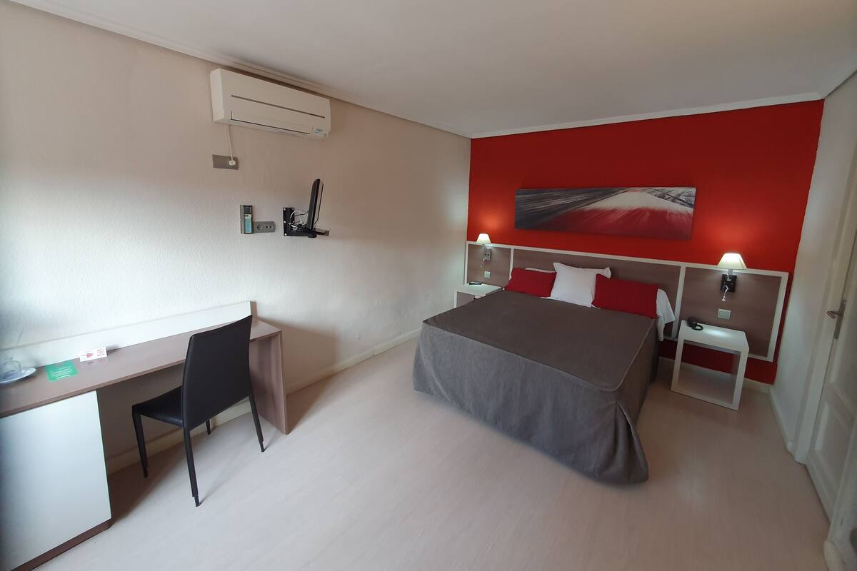 Una habitación de hotel con cama, escritorio, silla y mesitas de noche.