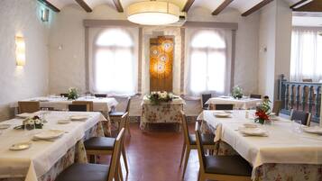Un espace repas avec des tables dressées pour le service, agrémenté d’un arrangement floral central et d’un lustre.