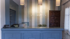 A reception desk with a blue counter, a telephone, and a sign that reads "HOTEL LA CARRETA". - Hotel La Carreta (Chiva)