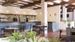 A restaurant interior with a bar area, seating, and decorative plants. - Hotel La Carreta (Chiva)