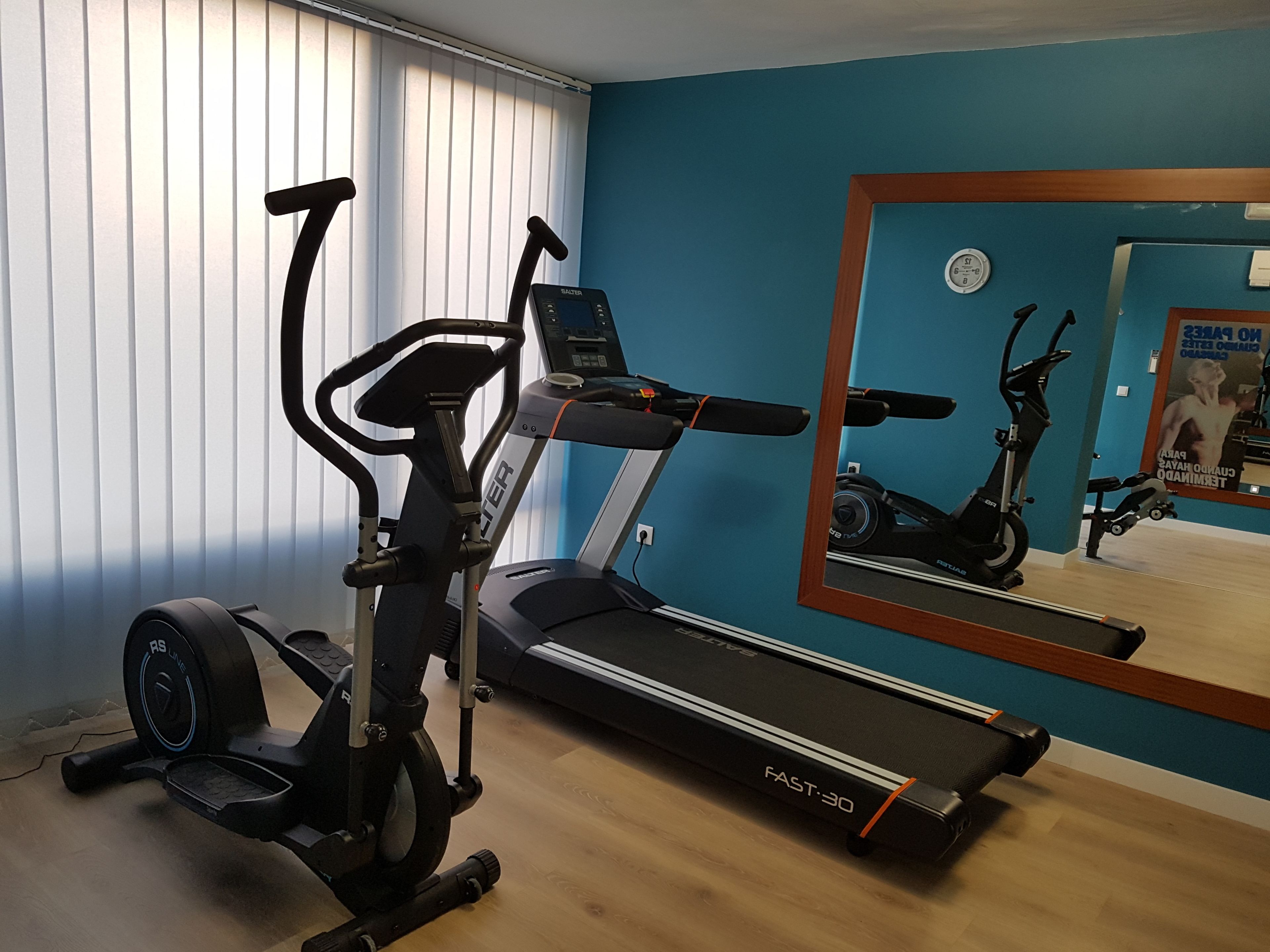 A home gym with a treadmill, elliptical, and stationary bike.