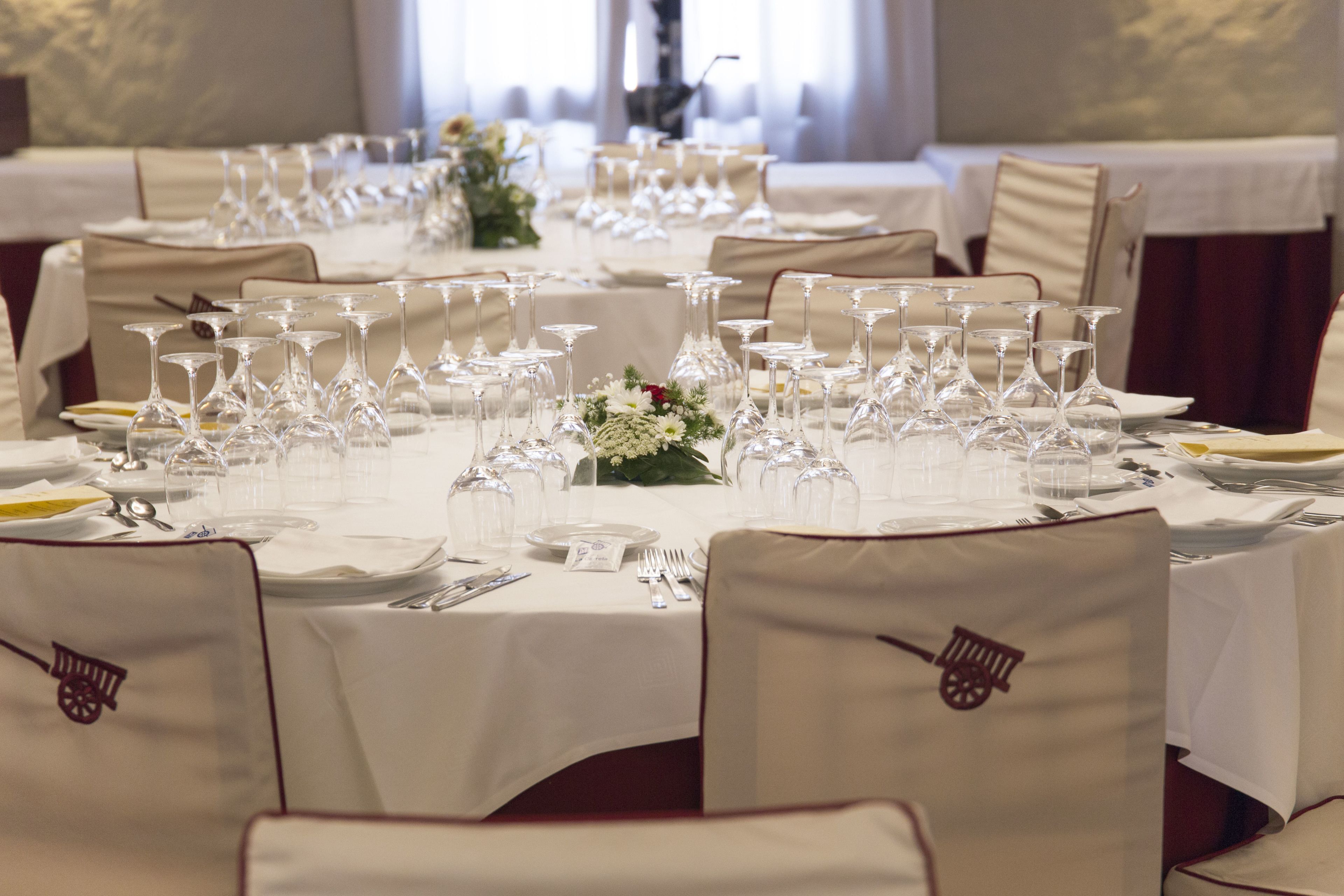 A banquet hall with tables set for a formal event, featuring white tablecloths, glassware, and floral centerpieces.