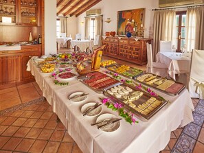 Enjoy a buffet-style meal in this inviting dining area with a long table set for a meal, surrounded by a variety of food items and traditional decor.