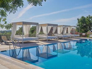 Relax by the pool surrounded by lush greenery and comfortable lounge chairs.