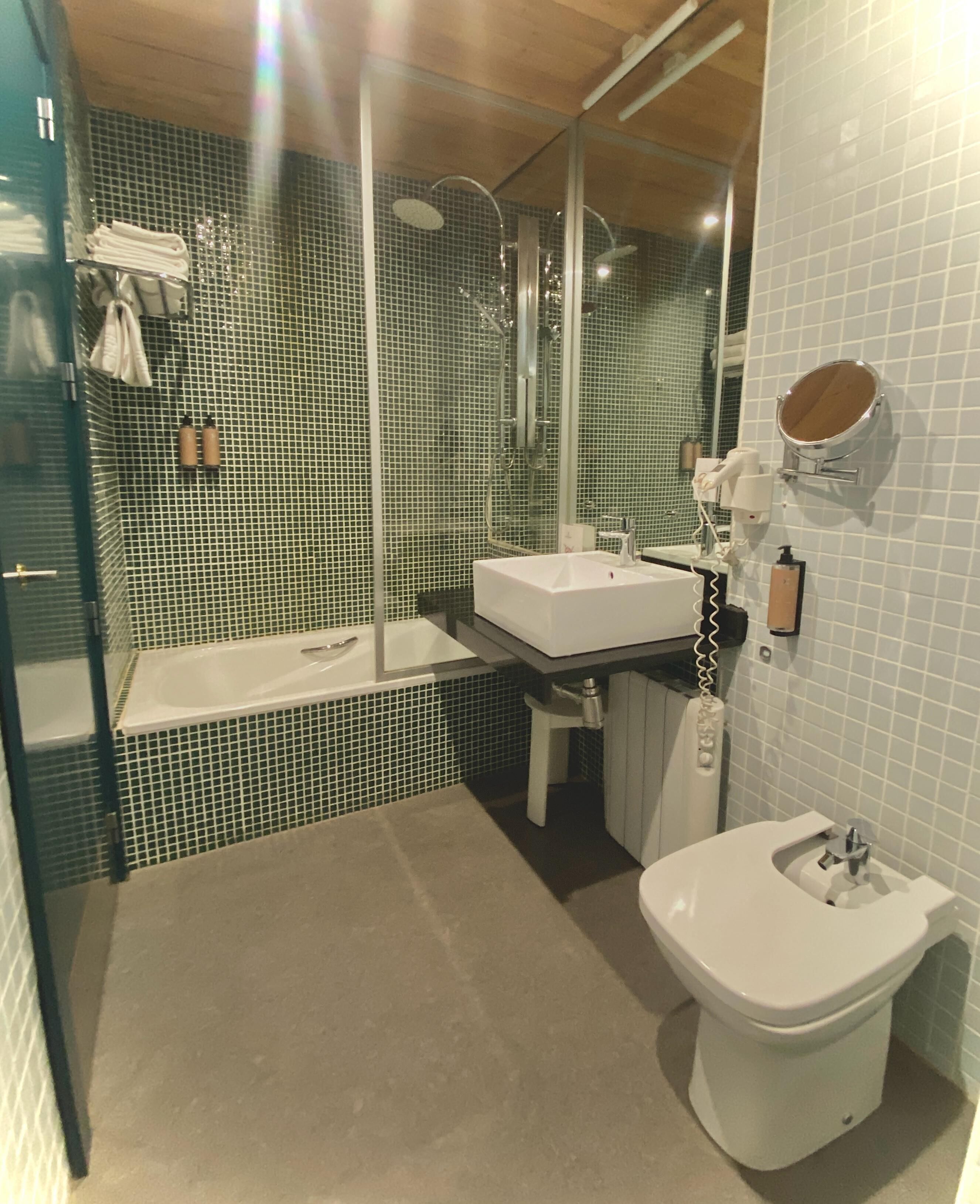 Een badkamer met een bad, een wastafel en een toilet. Handdoeken en toiletartikelen zijn zichtbaar.