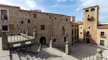 Un cortile con edifici in pietra, una scalinata centrale e una torre.