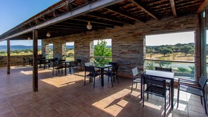 An outdoor patio with stone walls, metal beams, and a view of the countryside. - Hotel 4* Parque de Monfragüe (Torrejon El Rubio)