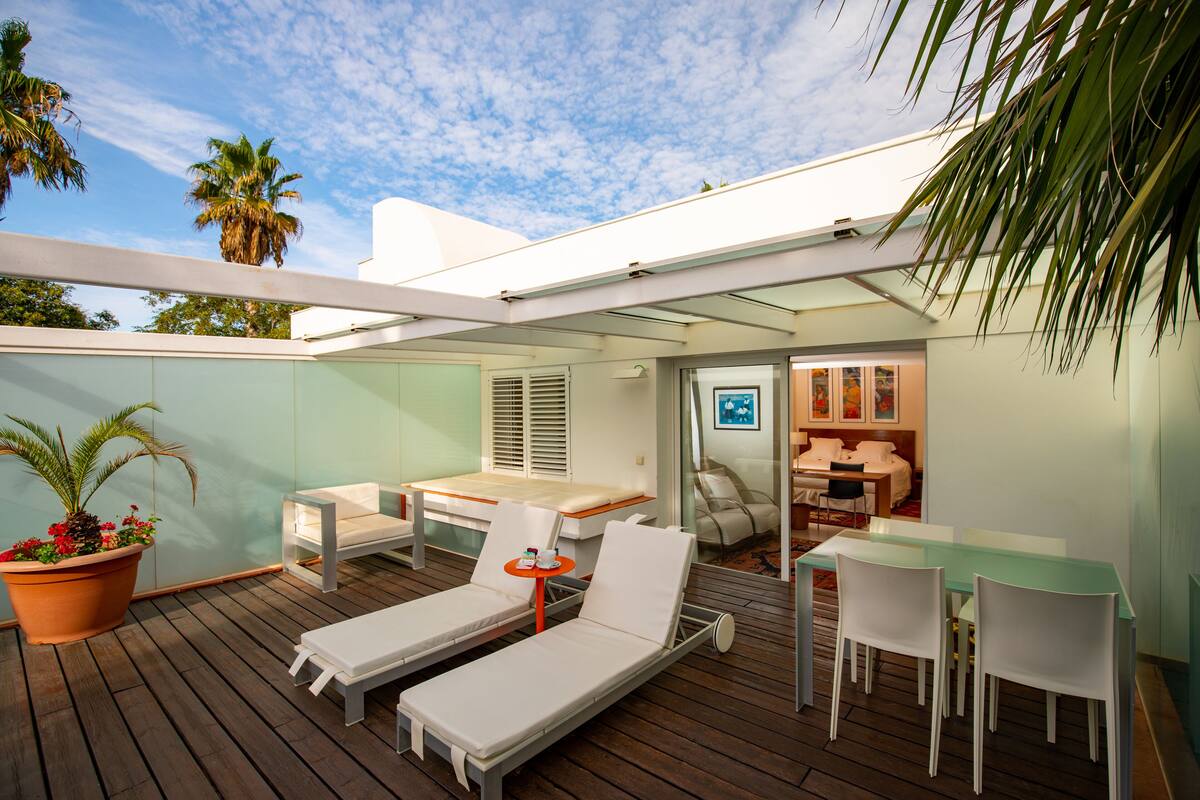 Un patio moderno al aire libre con sillones de descanso, una mesa de comedor y una pequeña zona de estar.