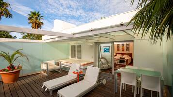 A modern outdoor patio with lounge chairs, a dining table, and a small seating area.