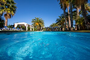 Een buitenzwembad, ligstoelen bij het zwembad