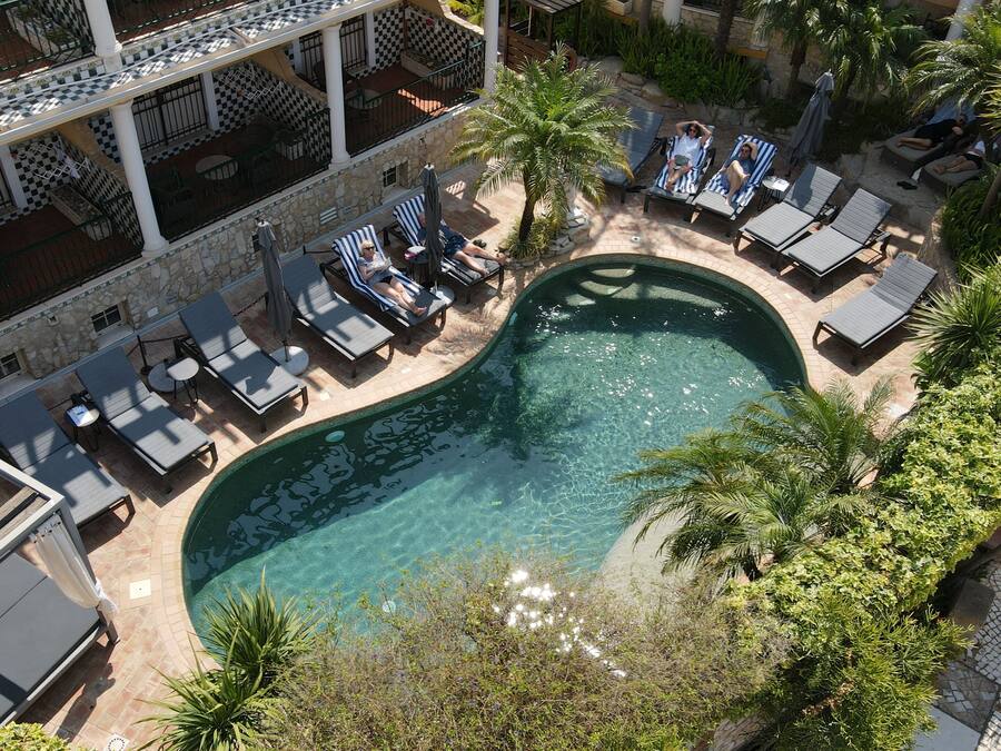 An aerial view of a resort with a swimming pool surrounded by lounge chairs and palm trees.