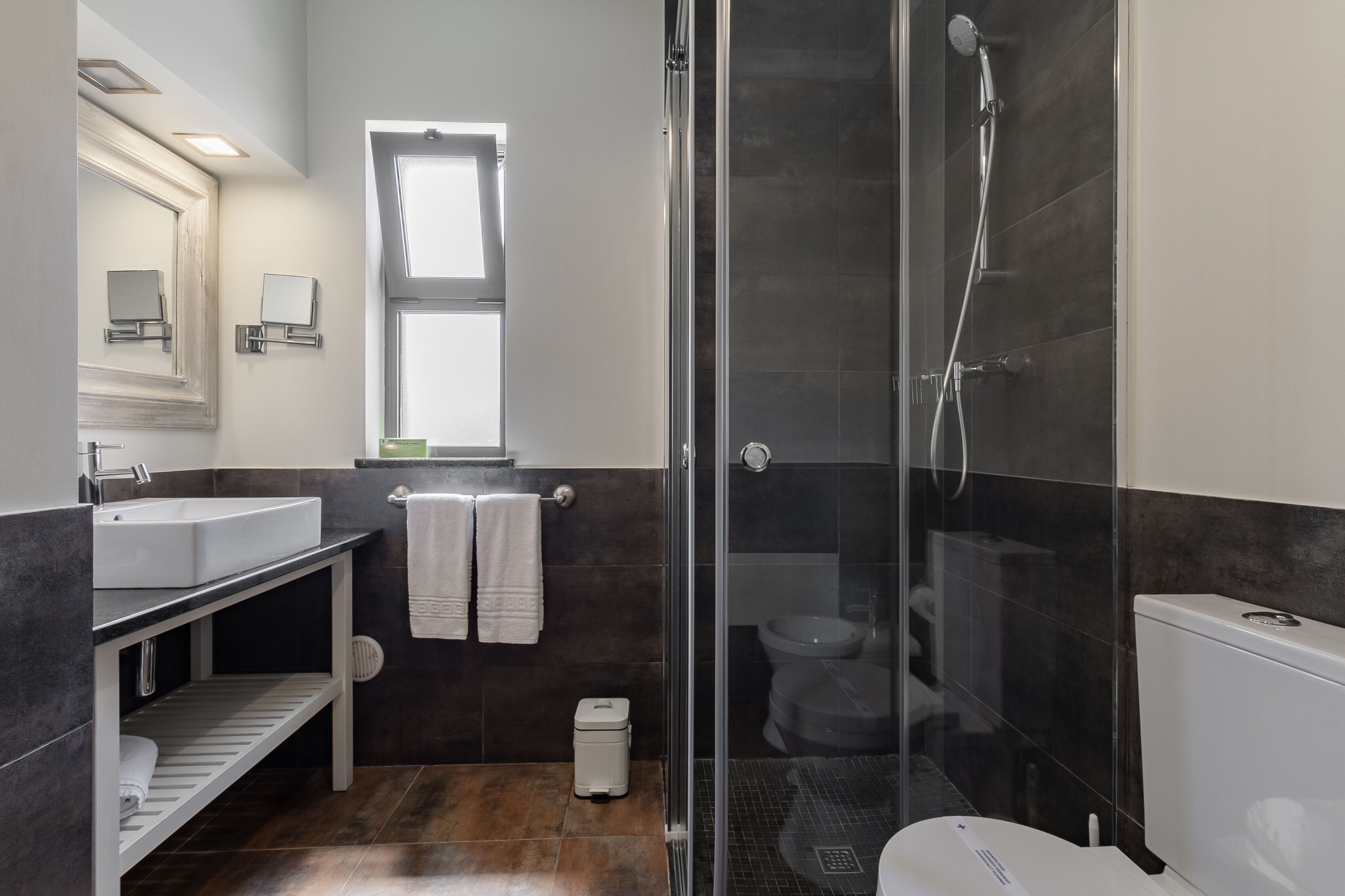 A modern bathroom with a glass-enclosed shower, a white sink, and a large mirror.