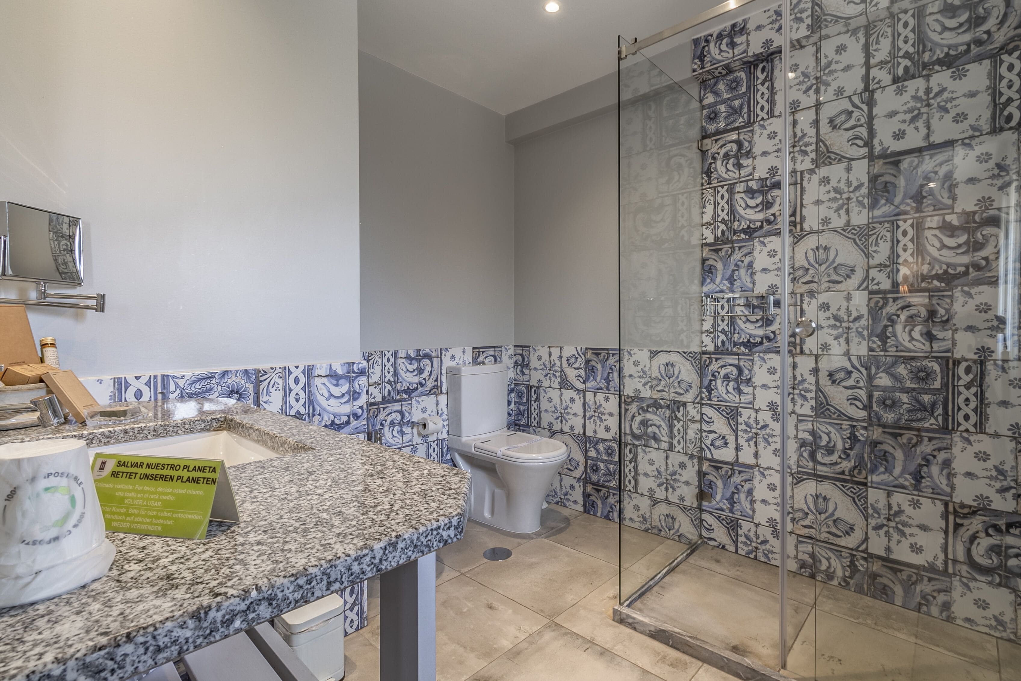 A bathroom with a marble sink, a toilet, and a shower area with patterned tiles.