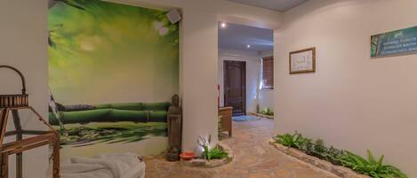 A stone-floored hallway with a Buddha statue, a green wall mural, and a sign indicating a Turkish bath.
