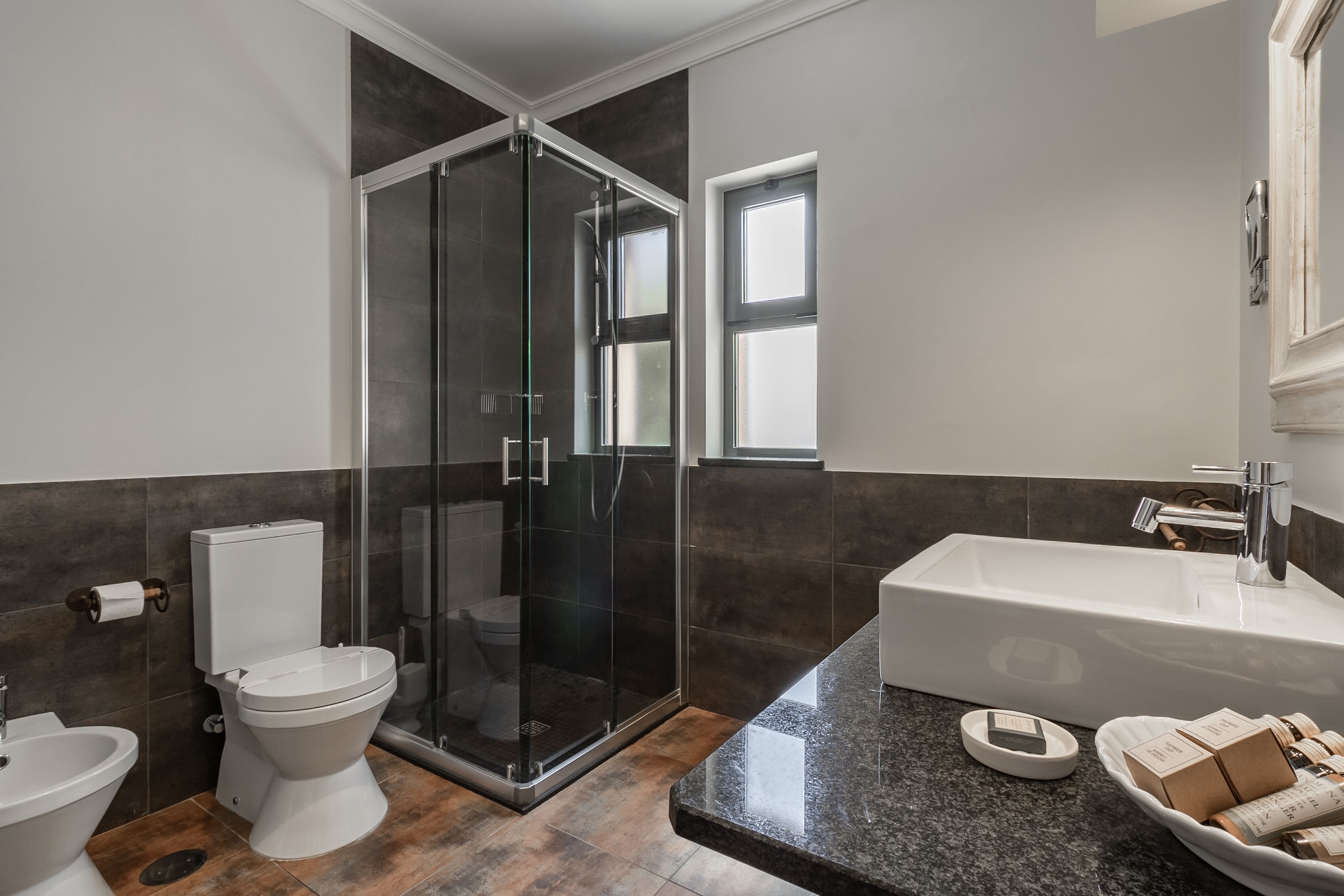 Une salle de bain moderne avec une douche à parois de verre, un lavabo blanc et des toilettes.