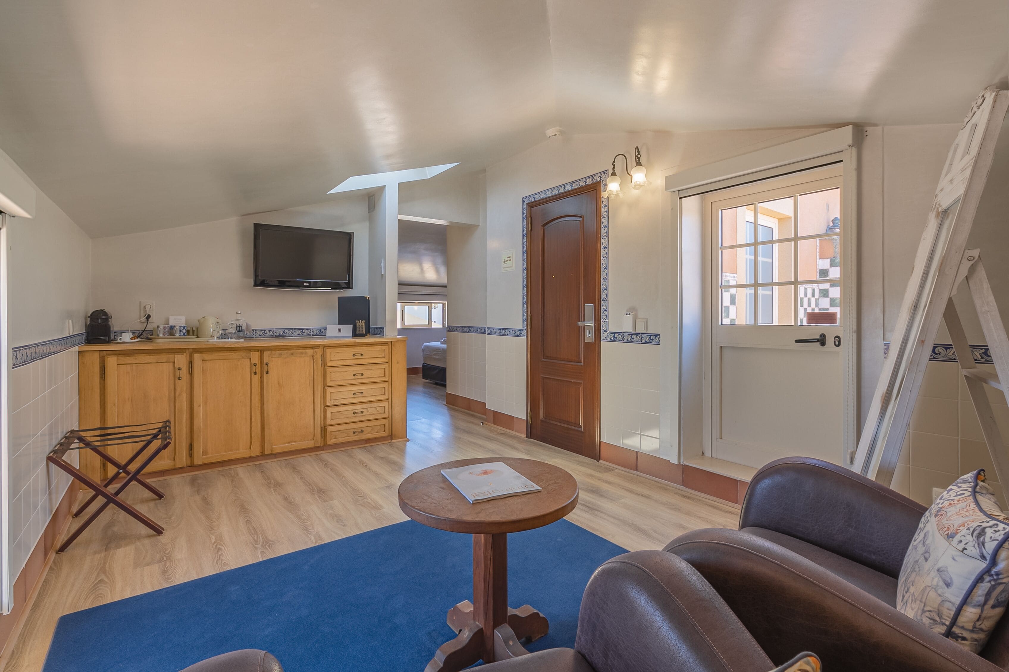 A compact living space with a kitchenette, a sofa, a small table, and a door leading to an outdoor area.