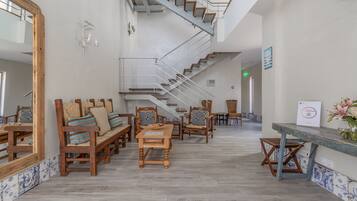 A spacious lobby with a central staircase, wooden furniture, and a tiled floor.
