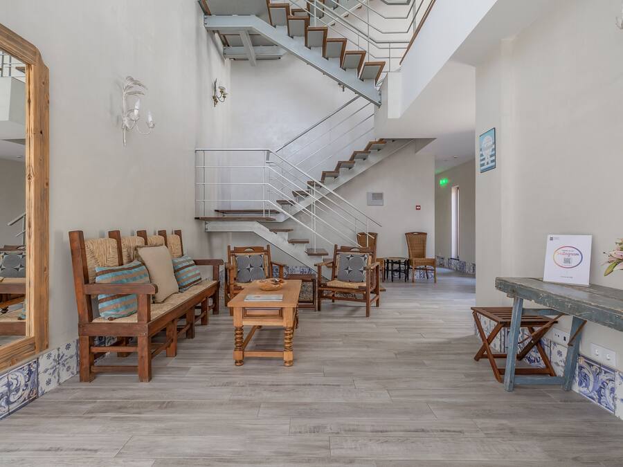 A spacious lobby with a central staircase, wooden furniture, and a tiled floor.