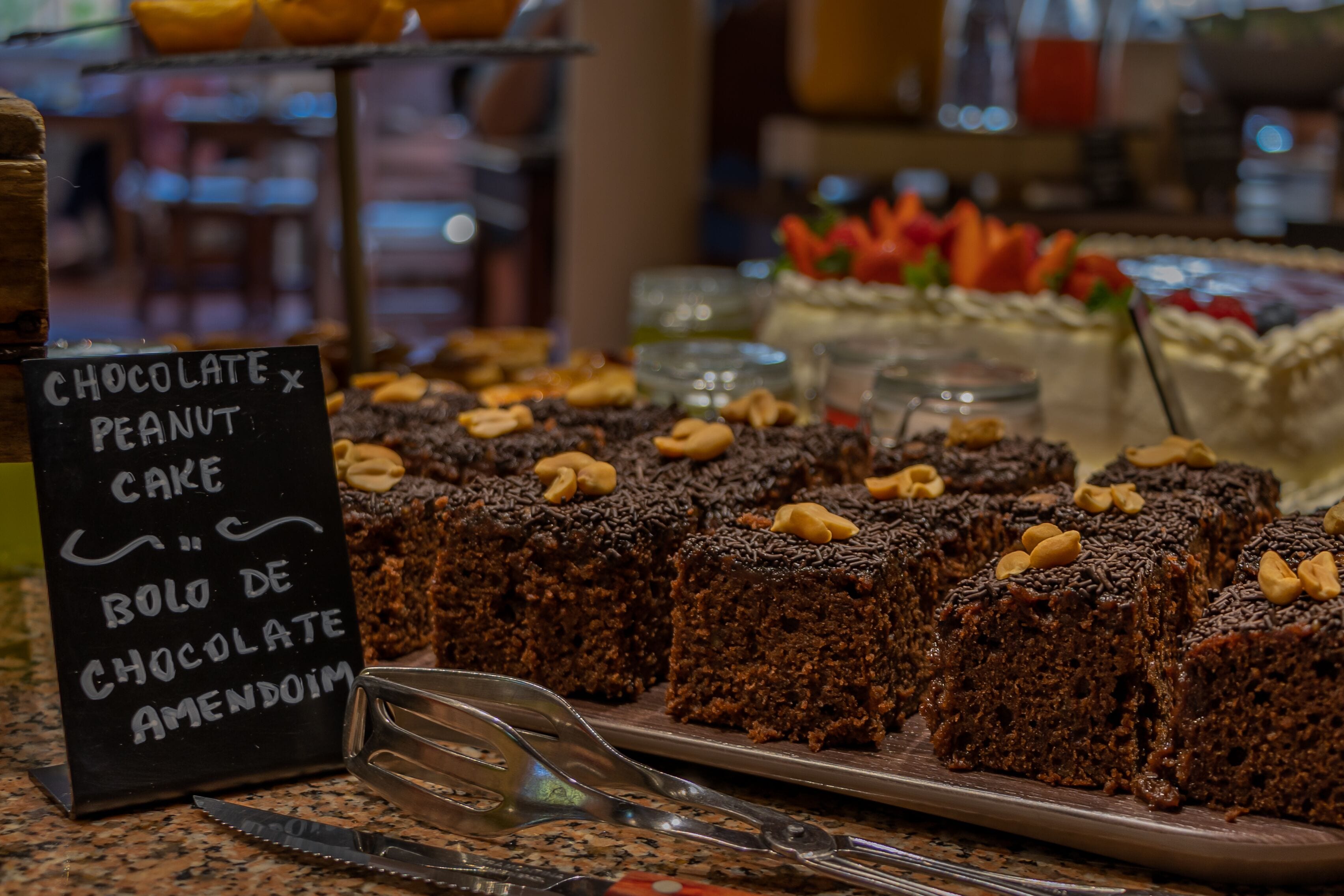 A display of chocolate and peanut cake with a sign indicating it is bolo de chocolate amendoim.
