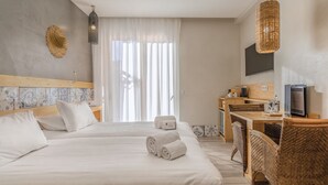 A hotel room with a large bed, a desk, a television, and a wicker chair. - Charming Residence & Guest House Dom Manuel I (Adults only) (Lagos)