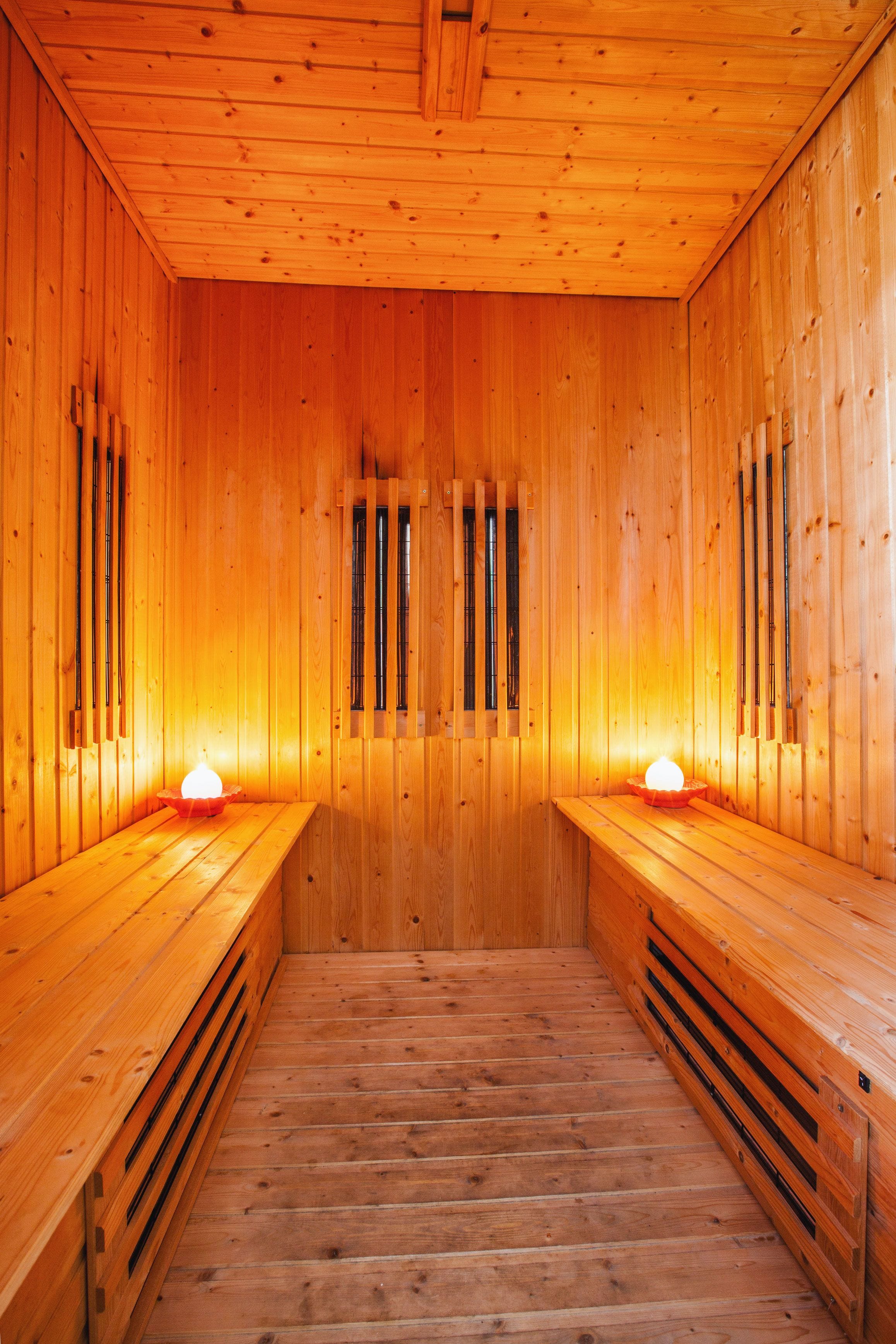 Una sauna de madera con bancos y un pasillo central.