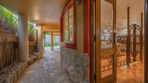 A stone-paved corridor with a wooden fence, a stone wall, and a door leading to a room with tiled flooring. - Charming Residence & Guest House Dom Manuel I (Adults only) (Lagos)