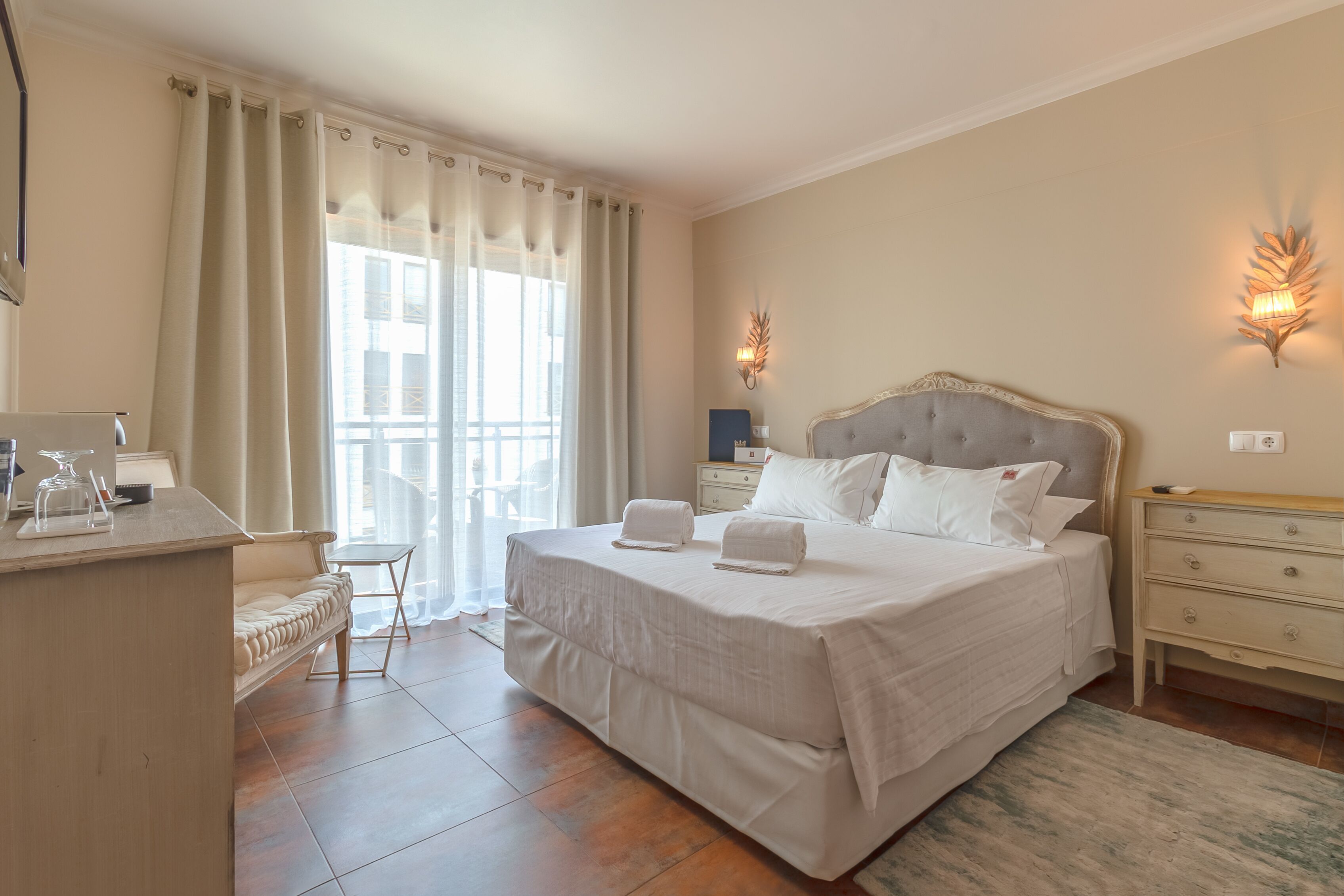 Un dormitorio amplio con una cama grande, una mesita de noche y un ventanal con cortinas.