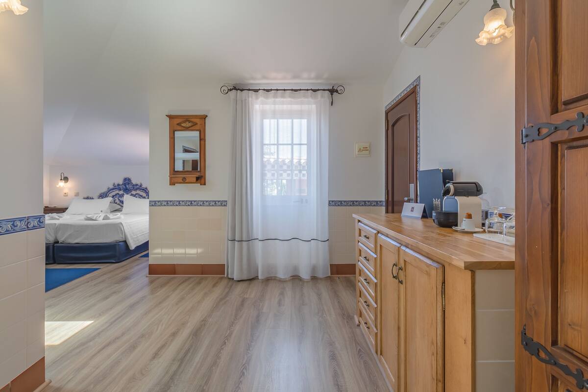 A hotel room with a bed, a bathroom, and a kitchenette.